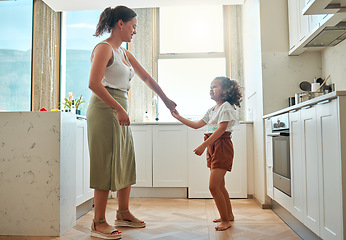 Image showing Mother and little daughter dancing having active fun together in the kitchen at home. Child and nanny having fun dancing to music and playing