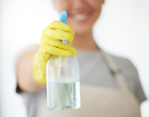 Image showing One unrecognizable woman holding a cleaning product while cleaning her apartment. An unknown domestic cleaner wearing latex cleaning gloves