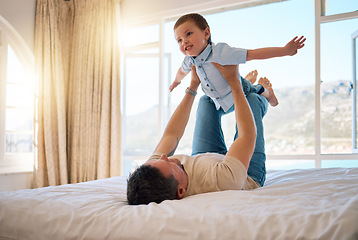 Image showing Cheerful caucasian father playfully lifting his son while spending the morning having fun in bed together. Single father playing a game with his little boy at home