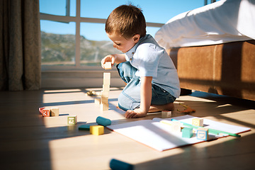 Image showing Little boy building a tower with wooden blocks. Adorable caucasian child stacking toys while developing fine motor skills and hand-eye coordination. Boy playing with building blocks or wooden cubes