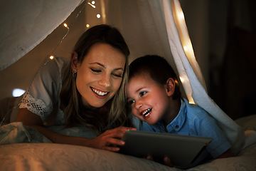 Image showing a beautiful young smiling caucasian woman long under a blanket fort with her adorable little son. Young family of two streaming movies on the internet while having fun together at home