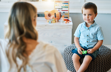 Image showing An adorable little boy sitting in his bedroom at home and talking to his mother. Happy male child bonding with his mom. Rearview of a blonde woman spending quality time with her young son on a weeken