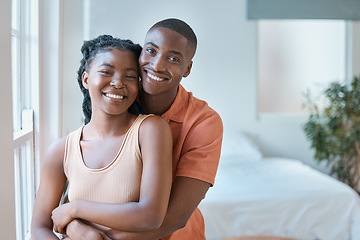 Image showing Portrait of a young black african american couple smiling as they lovingly embrace in the bedroom at home. An affectionate good looking black man and woman spending time together and looking in love