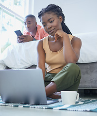 Image showing Young african american couple using tech devices, relaxing at home in the bedroom. Young woman using a laptop while sitting on the floor. Young man using a smartphone to send a text, lying on the bed