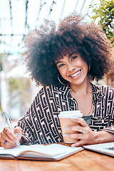 Image showing Smiling african american freelancer with curly afro working remotely in a cafe during the day. Mixed race entrepreneur writing notes in a book while enjoying a takeaway coffee. Hispanic businesswoman