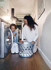 Image showing Adorable little African American boy with an afro smiling and faving fun while doing housework with him mother at home. mixed race portrait of a cute child folding laundry with his mom