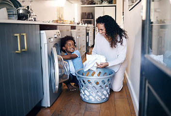 Image showing Adorable little African American boy with an afro smiling and faving fun while doing housework with him mother at home. mixed race shot of a cute child folding laundry with his mom