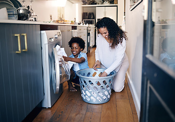 Image showing Adorable little African American boy with an afro smiling and faving fun while doing housework with him mother at home. mixed race shot of a cute child folding laundry with his mom