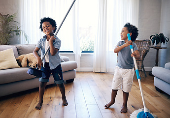 Image showing Two mixed race little boys playing with a mop and broom in the lounge at home. Excited siblings having fun playing with cleaning supplies at home. children singing and playing air guitar