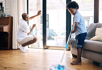 Image showing Mature african american dad and his young little son doing housework in the lounge at home. Black man and his boy having fun while cleaning their home together. Black boy and his dad cleaning