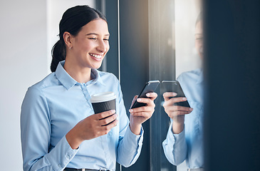 Image showing Happy young mixed race businesswoman browsing on a cellphone while drinking a cup of coffee at a window in an office. One female only texting and using social media apps online during a break at work