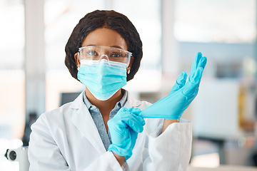 Image showing Im ready to change the world. Portrait of a young scientist putting on gloves while working in a lab.