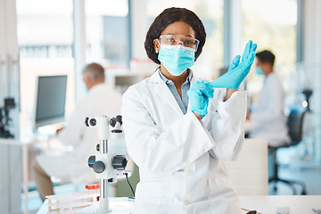 Image showing Ready for a day of lab work. Portrait of a young scientist putting on gloves while working in a lab.