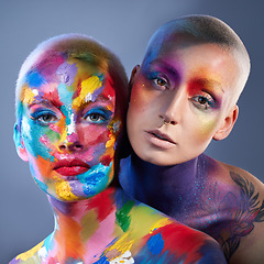 Image showing Add some colour to your life. Studio shot of two young women posing with multi-coloured paint on her face.