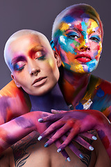 Image showing You are the canvas. Studio shot of two young women posing with multi-coloured paint on her face.