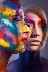 Image showing Feeling bright. Studio shot of two young women posing with multi-coloured paint on her face.