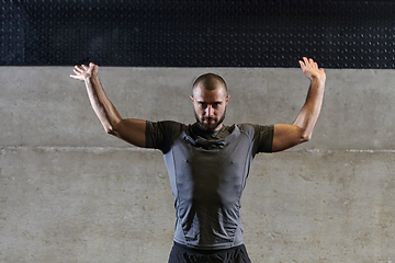 Image showing A muscular man working stretching exercises for his arms and body muscles in modern gym