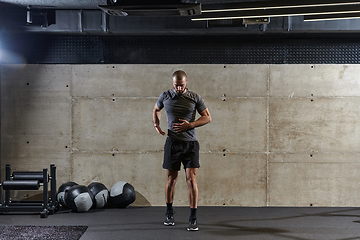 Image showing A muscular man working stretching exercises for his arms and body muscles in modern gym