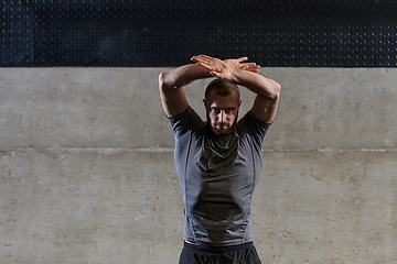 Image showing A muscular man working stretching exercises for his arms and body muscles in modern gym