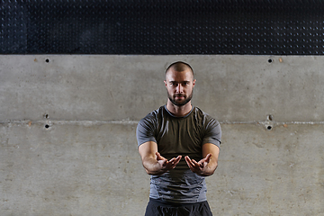 Image showing A muscular man working stretching exercises for his arms and body muscles in modern gym