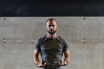 Image showing A muscular man working stretching exercises for his arms and body muscles in modern gym