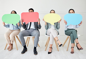 Image showing Let your voice be heard. Portrait of a group of businesspeople holding speech bubbles while sitting in line against a grey background.