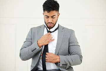 Image showing Getting all dressed up for his first day. a handsome young businessman tying his tie while getting ready for work.