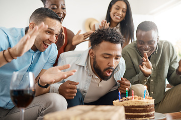 Image showing Make all your dreams come true. a young man blowing out his birthday candles at his party at home.