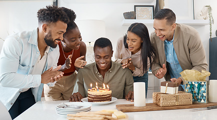 Image showing Awkwardly looking at my cake while they sing for me. a young man celebrating his birthday with friends at home.