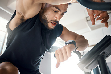 Image showing Times up for today. Low angle shot of a sporty young man checking his watch while exercising in a gym.