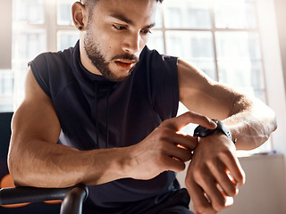 Image showing Set the clock for success. a sporty young man checking his watch while exercising in a gym.