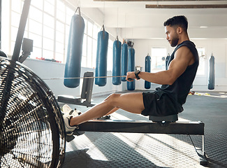 Image showing Commit to be fit. a sporty young man exercising on a rowing machine in a gym.