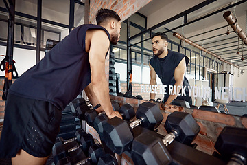 Image showing If you can face yourself, you can face anything. a sporty young man looking at himself in a mirror while exercising in a gym.