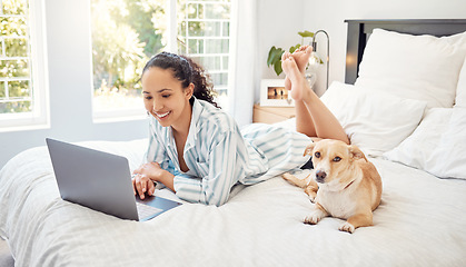 Image showing Whats better than this. a young woman using a laptop while relaxing on her bed at home.