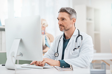 Image showing Research is essential to find out which treatments work best for patients. a mature doctor working on a computer in a medical office.