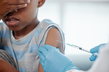 Image showing Trying to put on a brave face. a little boy looking scared while getting an injection on his arm from a doctor.