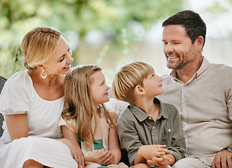 Image showing Affectionate family of four sitting on their sofa in the living room at home. A mother, father, son and daughter enjoying quality time together and bonding. Every parent wants the best for their kids