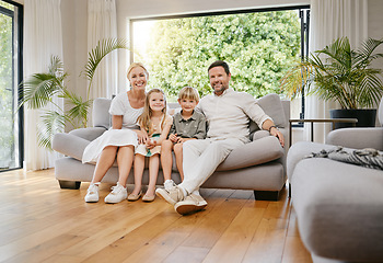 Image showing Fullbody young smiling caucasian family sitting on the couch together and bonding in a home lounge on a weekend. Mother and father sitting with children on a sofa