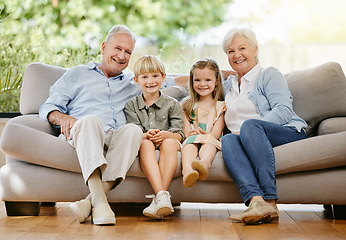 Image showing Portrait of an affectionate family of four sitting comfortable on their sofa in the living room at home. A grandmother, grandfather, grandson and granddaughter enjoying quality time together and bond