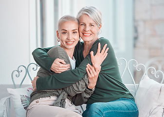 Image showing Cheerful senior mother hugging adult daughter. Loving caucasian mom giving her daughter a hug while sitting on a chair together at home. Mature woman looking happy to visit her daughter