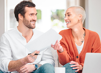 Image showing Ill leave this one to you. an affectionate young couple doing their finances at home on the sofa.