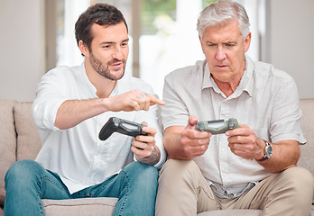 Image showing Showing dad what this whole gaming things is all about. a handsome young man showing his senior father how to play video games at home.