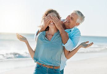 Image showing Hes full of surprises. a man covering his wifes eyes while on the beach.