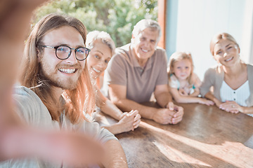 Image showing Smile for the camera. a handsome young man sitting with his family and taking selfies.