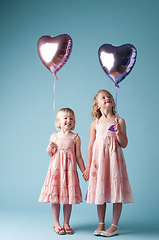 Image showing Together in this forever. two cute sisters playing with heart balloons against a studio background.