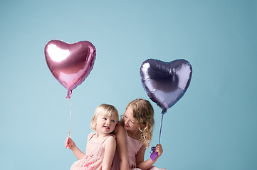 Image showing Ill always care about you. two cute sisters playing with heart balloons against a studio background.