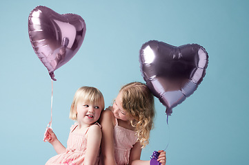 Image showing You deserve all the love. two cute sisters playing with heart balloons against a studio background.