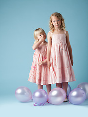 Image showing What a fun day. two sisters playing together in balloons against a studio background.