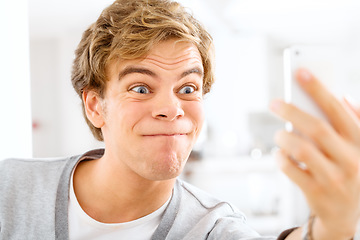 Image showing Always young at heart. a young woman making funny faces while taking selfies with his smartphone.