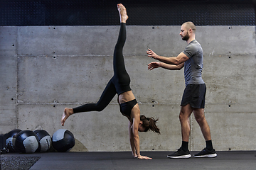 Image showing A muscular man assisting a fit woman in a modern gym as they engage in various body exercises and muscle stretches, showcasing their dedication to fitness and benefiting from teamwork and support